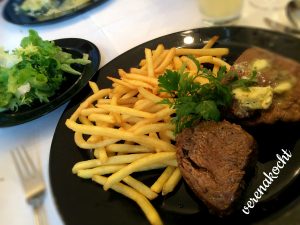 Steak mit Kräuterbutter auf Pommes mit Blattsalat